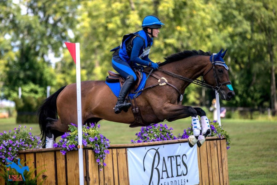 Interscholastic Eventing League rider jumping over a wooden rollback on a cross-country course