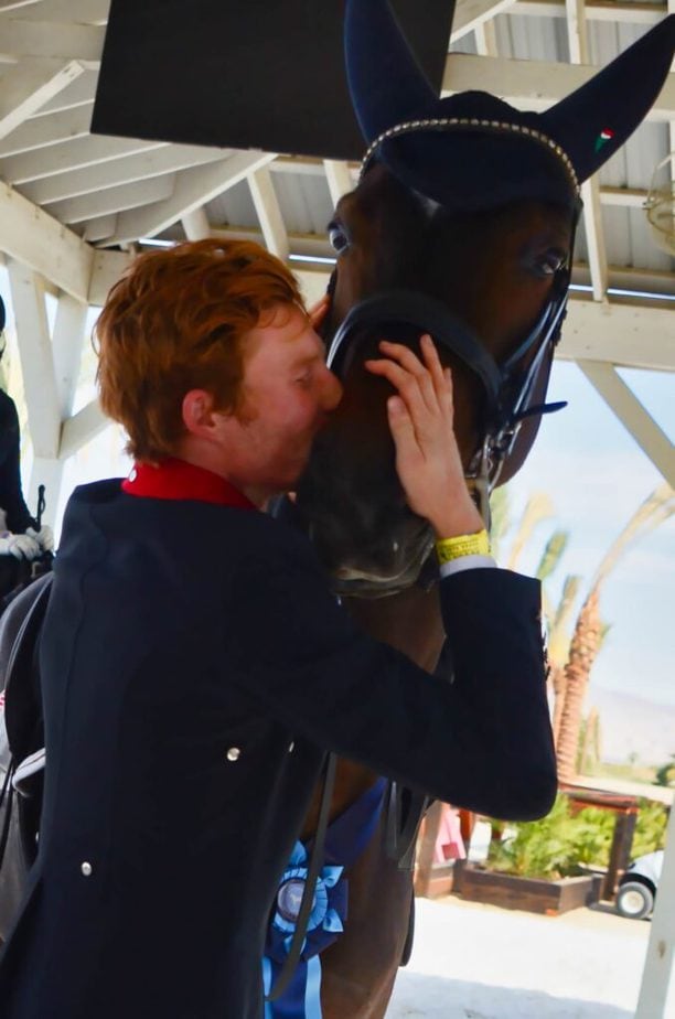 Ben Ebeling kissing a dark brown horse after a successful dressage test.